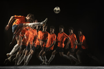 Young male football soccer player in motion and action in mixed light on dark background.