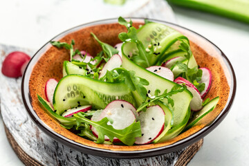 Green vegan salad from green leaves mix and vegetables. salad of radish, cucumbers, arugula. Food recipe background. Close up