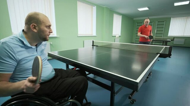 A man in a wheelchair plays ping pong. People with disabilities play table tennis. Rehabilitation of the disabled. Paralympic sport.