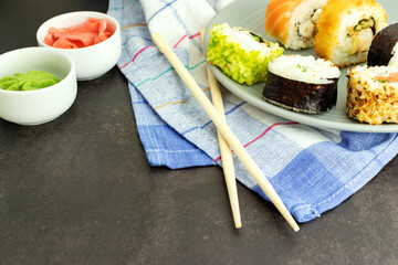 Delicious sushi food in a plate on a dark background in a close-up with sushi sticks, with place for text