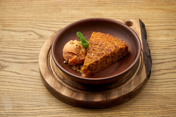 Appetizing carrot cake with apple sorbet ice cream in a clay bowl on a wooden background. A healthy dessert. Pastry