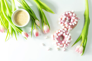 Obraz na płótnie Canvas Donuts with marshmallows, concept of March 8, women's day, pink tulips on a white background, top view