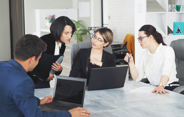 Three young successful business women in the office working together on a project
