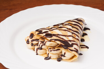crepe with banana and chocolate on a white plate