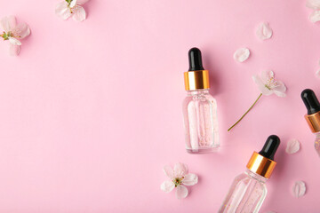 Beauty cosmetic skincare oil in bottle. Products with flower on pink background. Top view
