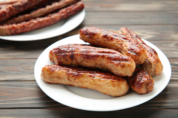 Grilled sausages on plate on brown wooden background