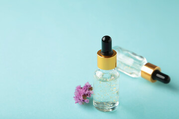 Beauty cosmetic skincare oil in bottle. Products with flower on blue background. Top view