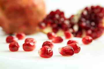 Pomegranate seeds, close-up, on a white background, on a pomegranate background, isolated, red, scattered, still life with a pomegranate