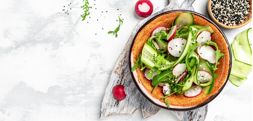 Healthy food nourishment diet detox dieting fresh vegetable salad of radish, cucumbers, arugula, vegan vegetarian food concept. Long banner format, top view