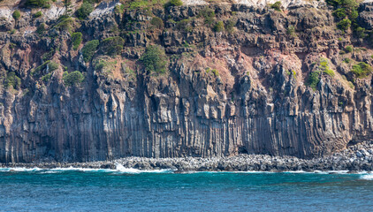 Steep coastal cliffs and interesting geological formation of basalt columns formation surrounding...