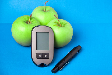 A device that measures glucose in the blood. Glaucometer with green apples.