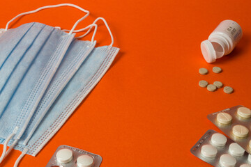 Face mask with pills lie on an orange background