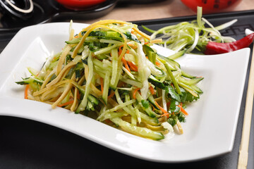 Chinese cuisine: cucumber salad with corn on a white plate