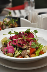 salad with vegetables and boiled beef on a white plate in a restaurant
