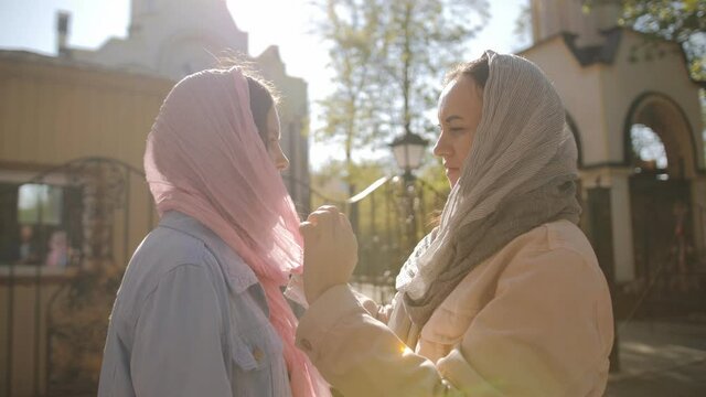 The mother ties a handkerchief on her daughter's head in front of the church. Celebrating the great day of Easter.