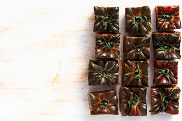 Black Tomato Dicced Squares. Top Down View on Wooden Cutting Board. Copyspace.