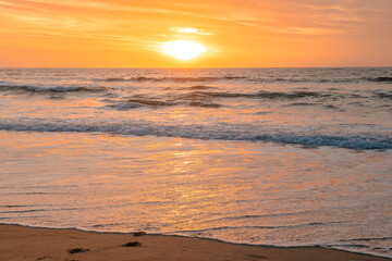 Footprints in the sand in front of the ocean during sunset, calm ocean and beautiful colorful sky, California