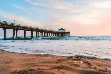 Manhattan beach pier at sunset, orange-pink sky with bright colors, beautiful landscape with ocean and sand