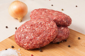 raw beef cutlets with onions on a wooden Board