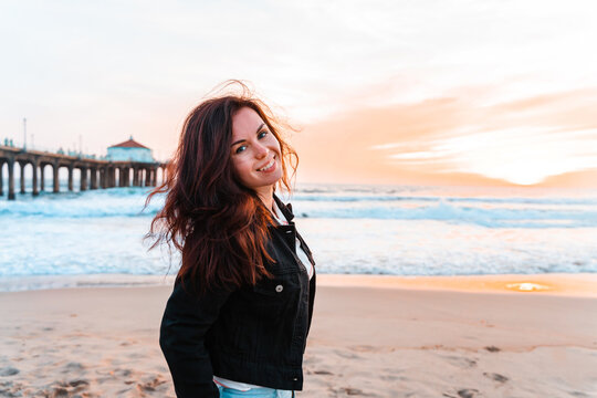 Beautiful young woman walks on the beach in Los Angeles with a bright sunset