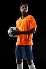 Portrait of young African soccer player posing isolated on black background. Concept of sport.