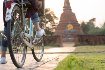 Female tourist riding a tourist bike at an old temple in Thailand.