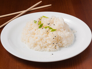 rice is garnished with green onions and sesame seeds on a white plate