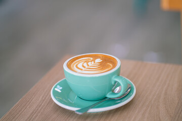Hot latte art coffe in green cup on wood table