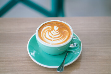 Hot latte art coffe in green cup on wood table