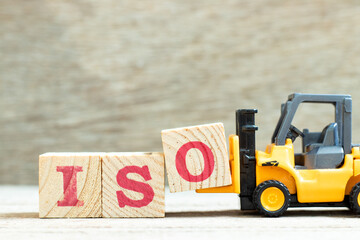 Toy forklift hold letter block o to complete word iso on wood background
