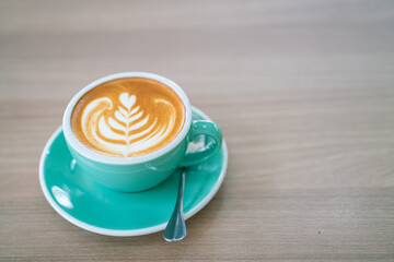 Hot latte art coffe in green cup on wood table
