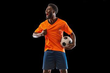 Portrait of young African soccer player posing isolated on black background. Concept of sport.