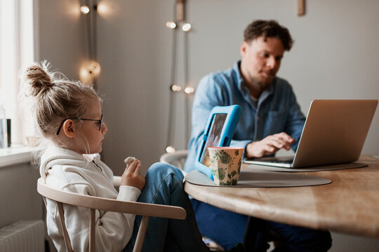 Girl using digital tablet, father in background