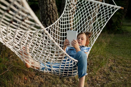 Girl on hammock using digital tablet