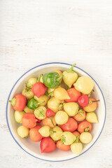 colorful hot peppers in a bowl on wooden table