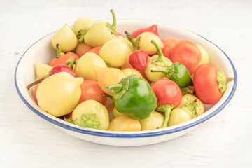 colorful hot peppers in a bowl on wooden table