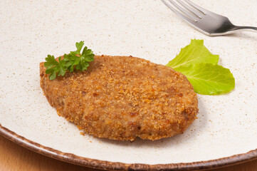chicken cutlet decorated with greens on a light plate