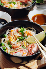 romantic dinner for two. Asian cuisine, rice noodles with shrimp and seafood, green peas and onions. soy sauce and various fresh vegetables. romantic dinner in black plates with Japanese chopsticks