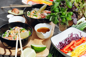 romantic dinner for two. Asian cuisine, rice noodles with shrimp and seafood, green peas and onions. soy sauce and various fresh vegetables. romantic dinner in black plates with Japanese chopsticks
