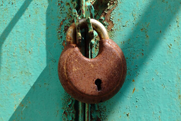 rusty padlock on a green metal doors