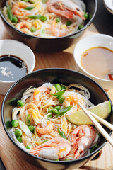 romantic dinner for two. Asian cuisine, rice noodles with shrimp and seafood, green peas and onions. soy sauce and various fresh vegetables. romantic dinner in black plates with Japanese chopsticks
