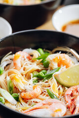 romantic dinner for two. Asian cuisine, rice noodles with shrimp and seafood, green peas and onions. soy sauce and various fresh vegetables. romantic dinner in black plates with Japanese chopsticks