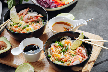 romantic dinner for two. Asian cuisine, rice noodles with shrimp and seafood, green peas and onions. soy sauce and various fresh vegetables. romantic dinner in black plates with Japanese chopsticks
