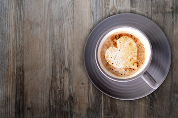 Cappuccino coffee in gray cup and saucer on an old wooden table, ruddy fresh croissants, heart-shaped foam, concept fresh pastries, morning coffee, caffeine addiction, energy boost