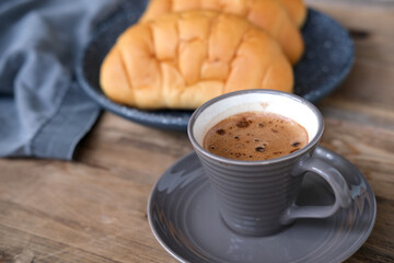Cappuccino coffee in gray cup and saucer on an old wooden table, ruddy fresh croissants, concept fresh pastries, morning coffee, caffeine addiction, energy boost