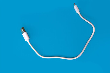 closeup white usb cable for a computer on a blue background, modern technological high-speed device on a blue background, concept of electronic technologies for home