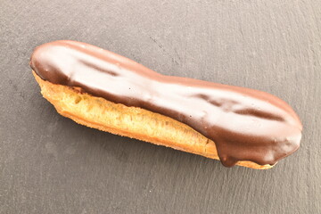 One chocolate eclair, close-up, on a slate board, top view.