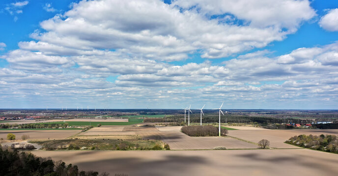Aerial view of monotonous farmland in flat landscape with wind turbines under cloudy sky