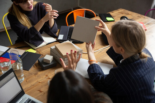 Businesswoman analyzing product with female colleagues at conference table in board room