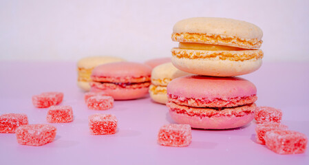 Pink and beige macarons on pink background with small rose candy. French Pastel Macaroons. Selective focus